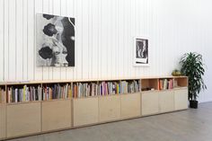 an empty room with bookshelves and pictures on the wall behind them, in front of a potted plant