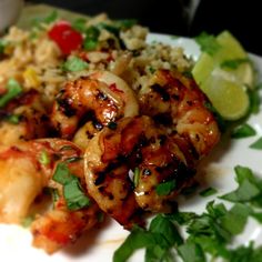 a plate with shrimp, rice and cilantro on it