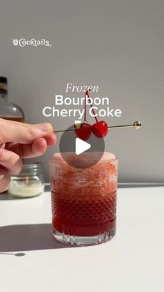 a person holding a cherry on top of a drink