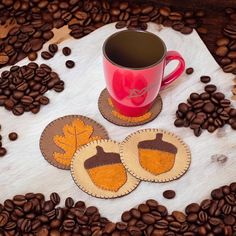 three coasters sitting on top of coffee beans next to a red cup and saucer