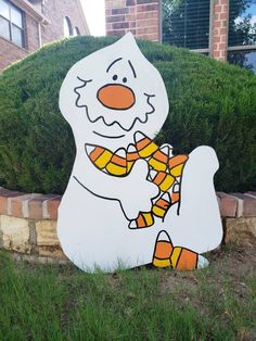 a snowman with candy canes in front of a brick wall and shrubbery