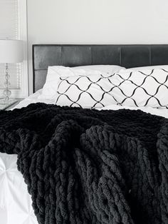 a black and white photo of a bed with blankets on it's headboard