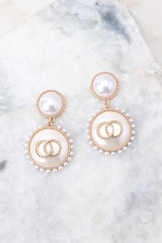 Look elegant and glamorous with these Graceful Glamour Pearl Earrings! These earrings put the “glam” in glamourous! Shine bright with these exquisite earrings and get ready to be the belle of the ball! These earrings feature pearl studs, gold detailing, small pearls circling larger pearl dangles, and a secure post backing. • Earrings measure 2" in length and 1" in width Feminine Pearl Earrings For Evening, Glamorous Pearl White Earrings For Formal Occasions, Feminine Evening Pearl Earrings, Feminine Pearl White Pearl Earrings For Party, Glamorous Pearl White Pearl Drop Earrings, Glamorous Pearl Earrings For Party, Glamorous Pearl Earrings For Formal Occasions, Chic Gold Clip-on Earrings With Pearl Drop, Glamorous Formal Pearl Earrings