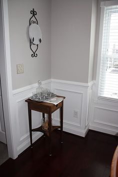 the corner of a room with a small table and clock on the wall above it