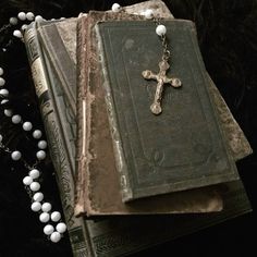 an old book with a cross on it next to a beaded necklace and rosary