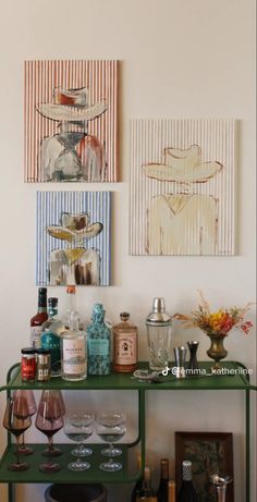 there are many bottles and glasses on the shelf in this room with pictures above it