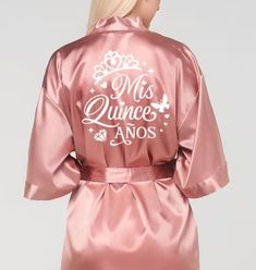 Introducing our luxurious satin quinceañera robe, the perfect keepsake for your special day! Soft and silky, this personalized robe can be customized with your name and event date, making it a beautiful reminder of your quinceañera for years to come. Whether you're getting ready or just want to feel pampered, this robe adds a touch of elegance to your celebration. We also offer matching robes for your damas and the mother of the quinceañera, ensuring everyone looks and feels their best. Celebrate in style and cherish the memories forever! Quince Robe, Surprise Dance Outfits Quinceanera, Pink Quince Theme, Surprise Dance Outfits, Green Quinceanera Theme, Red Quinceanera Ideas, Court Outfit, Quinceanera Pink, Pink Quince