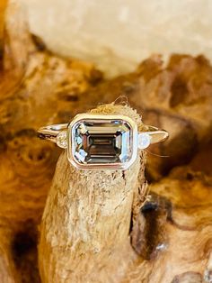 an engagement ring with a green tourmaline surrounded by wood