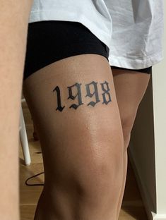 a woman's leg with the number 999 tattooed on her left side and an arrow in the middle