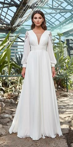 a woman wearing a white dress standing in front of some plants