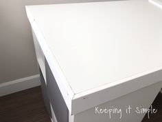 a white desk with two drawers on top of it and a wood floor underneath the table