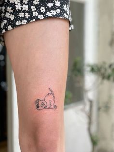 a woman's leg with a small tattoo of a dog laying on her stomach