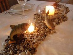 a table with two fish on it and some candles in the middle that look like pebbles