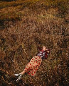 a woman laying on the ground in tall grass