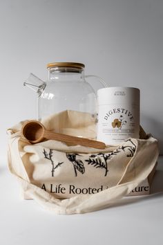 a glass jar with a wooden spoon sitting on top of it next to a tea towel