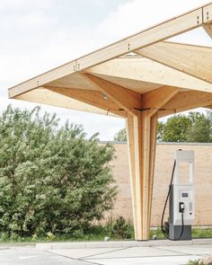 an empty gas station with a wooden roof and no one at the pumps or charging stations