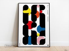 a black and white poster with colorful shapes on the wall next to a wooden floor