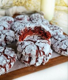 a pile of red velvet crinkle cookies sitting on top of a wooden cutting board