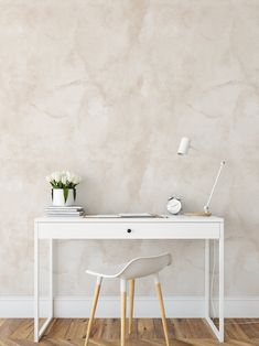 a white desk and chair in front of a wall with a flower pot on it