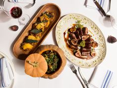 a table topped with plates and bowls filled with food next to utensils on top of a white table cloth