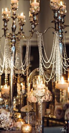 a chandelier filled with lots of candles next to a table topped with flowers