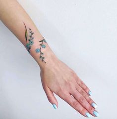 a woman's hand with blue flowers on the left wrist and green leaves on the right arm