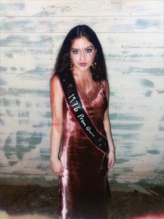 an old photo of a woman in a dress with a sash around her neck and eyes closed