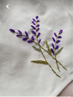 some purple flowers are on a white cloth