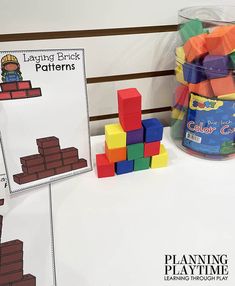 a table topped with lots of different colored blocks next to a bucket of building blocks