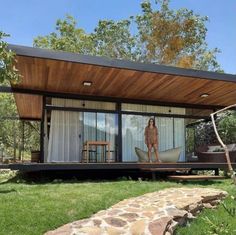 a woman standing in the doorway of a tiny house on stilts with sliding glass doors