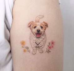 a small dog tattoo on the right side of the thigh, with flowers around it