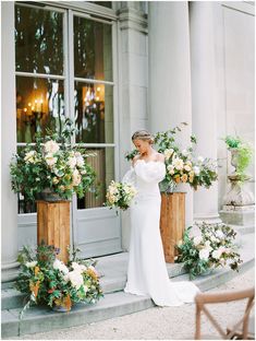 a woman in a white dress standing on steps with flowers