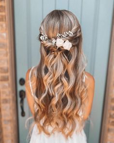 a woman with long hair and flowers in her hair is looking into the mirror while wearing a white dress