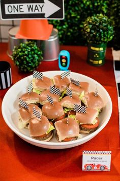 a plate full of sandwiches on a table with one way sign in the back ground