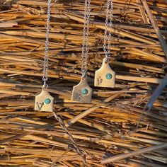 three silver necklaces with turquoise stones hanging from them on some sticks in the grass