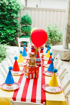 a table topped with lots of red, white and blue cones next to a balloon