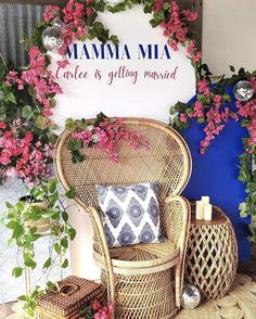 a wicker chair with pink flowers on it in front of a sign that says mamma mia