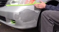 a man sitting on the side of a car with his hand on the front bumper