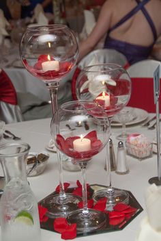 two wine glasses with candles in them on a table set for a wedding reception or special occasion