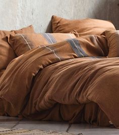 an unmade bed with brown linens and striped pillows