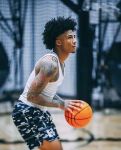 a young man holding a basketball in his right hand and wearing shorts on the other side