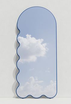 a mirror that is on the side of a wall with clouds in the sky behind it