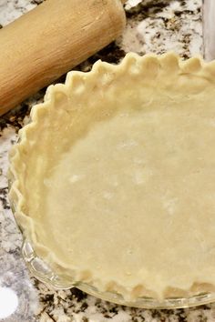 an uncooked pie crust sitting on top of a counter next to a rolling pin