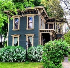 a blue house with trees and bushes around it