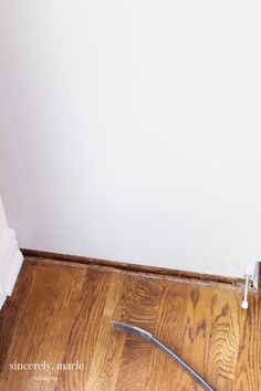 a bathroom with a toilet and wood flooring next to a white towel rack on the wall