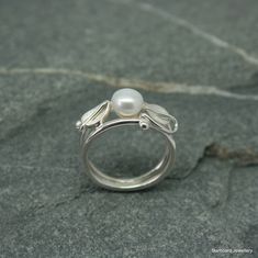 Handcrafted sterling silver, art nouveau style ring with single freshwater pearl. Created in our own studio In Cornwall A beautiful, flowing art nouveau style pearl ring with silver leaves and vine wrapped around two silver wire bands. The leaves have a satin finish and the silver bands are highly polished UK finger sizes  J to T Other sizes  request  All my jewellery comes in a presentation gift box.  All my designs are hand made and no two are exactly the same.   Thank you for your time. Please note that international shipping fees do not include possible custom charges for your country and you will be solely responsible for payment of these charges.  We are required by law to fully disclose the contents and value of the items in your package for Customs purposes.  Your local customs off White Gold Sterling Silver Rings With Pearl Drop, Handmade Elegant Sterling Silver Pearl Ring, Delicate Silver Pearl Ring For Anniversary, Handmade Sterling Silver Pearl Ring, Unique Sterling Silver Pearl Ring For Wedding, Handmade Silver Pearl Ring, Delicate Silver Pearl Ring Gift, Elegant Handmade Pearl Promise Ring, Dainty Silver Pearl Drop Ring