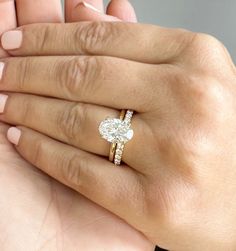 a woman's hand holding a ring with a heart shaped diamond on the band