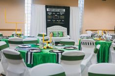 tables and chairs are set up for an event with green tablecloths on them