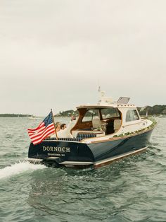 a small boat with an american flag on the front is in the water near shore