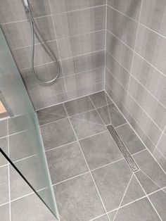 a walk in shower sitting next to a glass door on a tiled bathroom floor and wall